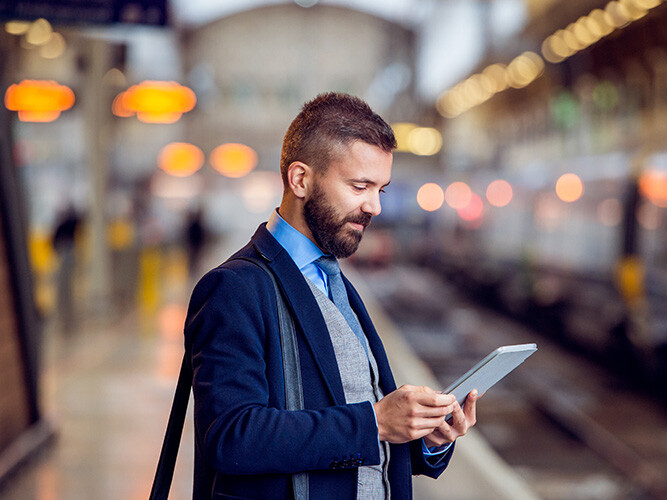 Man står på en tågstation och kollar på sin ipad